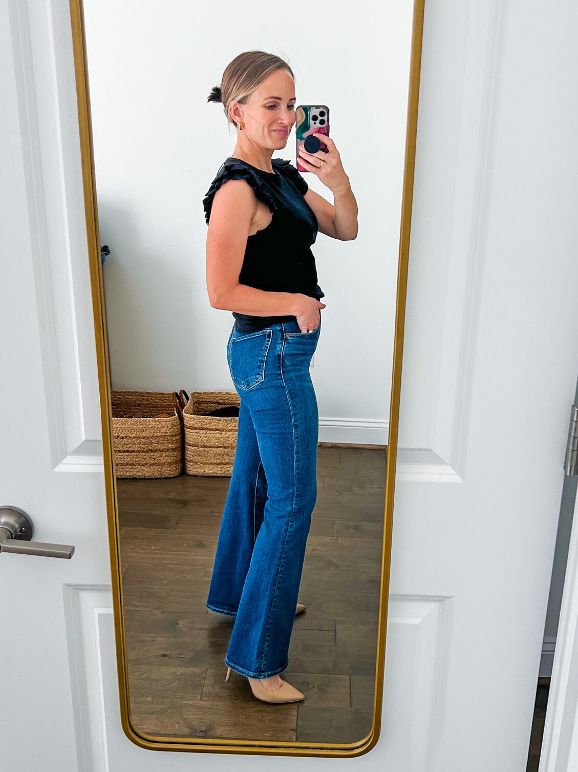 TeriLyn Adams showing the side details of jeans in Ultra High Rise Flare Jean in black and dark blue wash