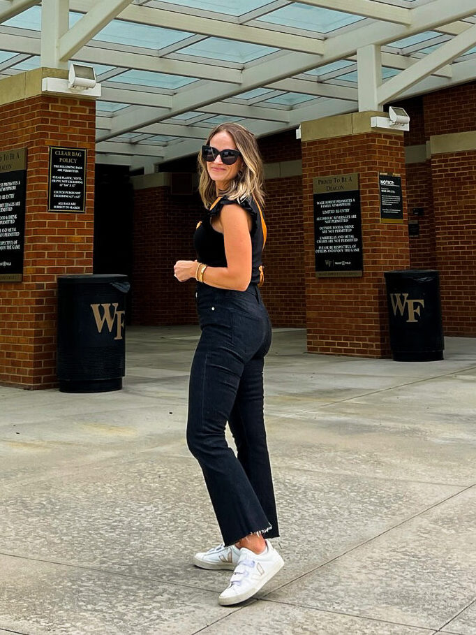 woman wearing black top and black jeans one of the outfits for what to wear to a football game